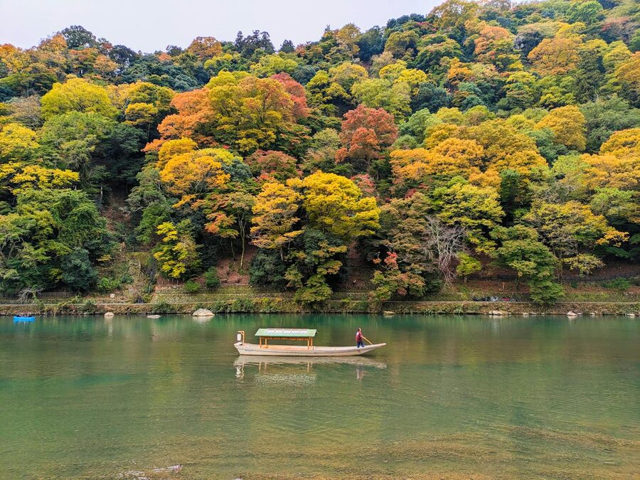 Autumn view of Arashiyama with a riverboat on the Hozu