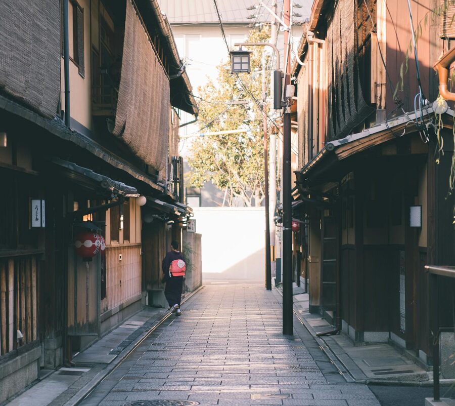 Narrow traditional Gion alleyway with a woman walking in kimono