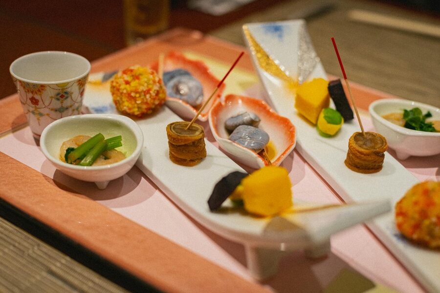 Multi-course kaiseki meal with sashimi and grilled dishes presented on lacquered trays
